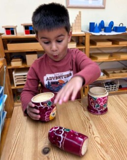 Lyonsgate Montessori School Casa student exploring the wonder of a matryoshka doll.