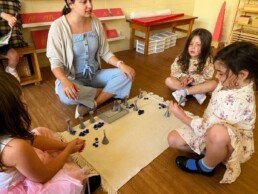 Lyonsgate Montessori School Casa students working with their Montessori guide on a memory game of numbers.