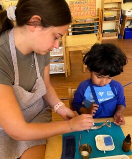 Lyonsgate Montessori School Casa student receiving a presentation of the Montessori Polishing Silver activity, one of a number of increasingly complex polishing activities.