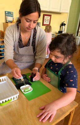 Lyonsgate Montessori School Casa student receiving a presentation of the Montessori Polishing Wood activity, one of a number of increasingly complex polishing activities.