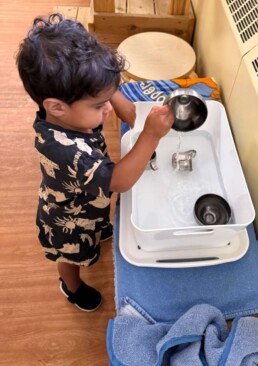 Lyonsgate Montessori School Toddler student engaged in sensory experience work by pouring water.