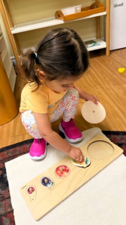 Lyonsgate Montessori School Toddler student building fine motor skills with a puzzle that can also be used for vocabulary development.