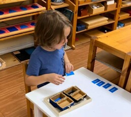 Lyonsgate Montessori School Casa student developing reading and literacy skills with the Montessori Adjective Box material.