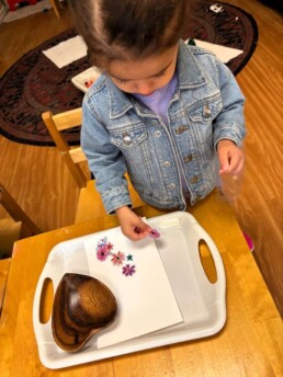 Lyonsgate Montessori Toddler student peeling and sticking sticker art.