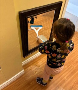 Lyonsgate Montessori School Toddler student learning a three-step process by washing the classroom mirror.