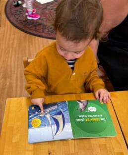 Lyonsgate Montessori School Toddler student enjoying a book while learning about the use and care of them.
