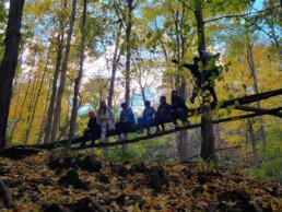 Lyonsgate Montessori School Elementary students climbing in the autumn woods.