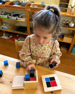 Lyonsgate Montessori School Casa student working with the Montessori Binomial Cube material -- a puzzle to recognize patterns and relationships in Casa and used again to learn algebraic concepts in Elementary.