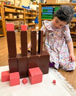 Lyonsgate Montessori School Casa student engaged in extension work with the Montessori Pink Tower and Brown Stairs materials, two of the first material presentations Casa students receive that can be used throughout their time in Casa.