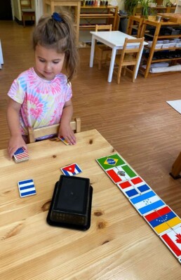 Lyonsgate Montessori School Casa student engaged in a matching activity with flags of the world.
