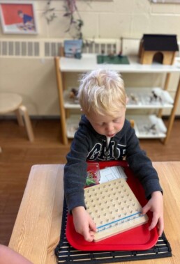 Lyonsgate Montessori School Casa student working with the Montessori Geo-Board material.