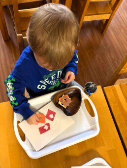 Lyonsgate Montessori School Toddler student engaged in a gluing activity to help build fine motor skills.