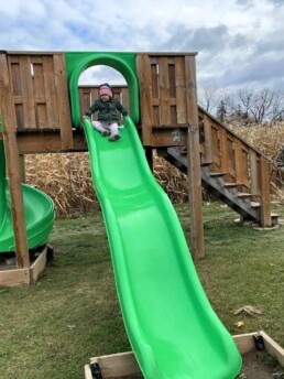 Lyonsgate Montessori School Toddler student enjoying a slide during a field trip to a farm.