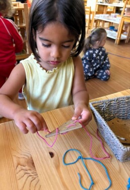 Lyonsgate Montessori School Casa student building fine motor skills with a threading activity.