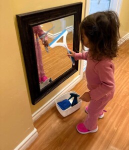 Lyonsgate Montessori School Toddler student taking care of her environment by mirror washing.