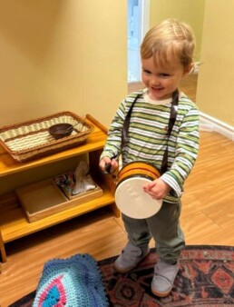 Lyonsgate Montessori School Toddler student exploring music sounds and vibrations through drumming.
