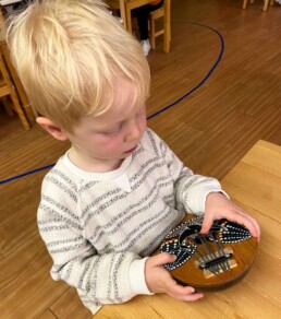 Lyonsgate Montessori School Casa student exploring a musical instrument.