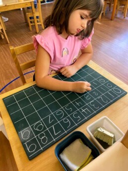 Lyonsgate Montessori School Casa student practicing writing the numbers 0-9 on a chalkboard.