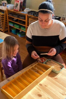 Lyonsgate Montessori School Casa student receiving a presentation with the Montessori Spindle Box material, which helps students experience the quantities associated with numbers.