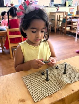 Lyonsgate Montessori School Casa student engaged in the Nuts and Bolts activity, which is a practical skill that also builds fine motor skills and focus.