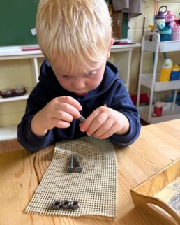 Lyonsgate Montessori School Casa student working with nuts and bolts to build fine motor skills and to develop concentration.