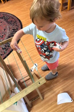 Lyonsgate Montessori School Toddler student learning to use the clothes pins for the classroom drying rack.