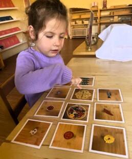 Lyonsgate Montessori School Casa student learning the French vocabulary for different pizza ingredients.
