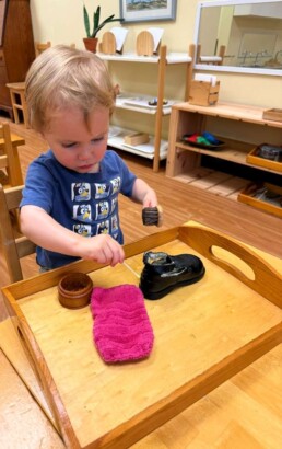 Lyonsgate Montessori School Toddler student engaged in the Montessori shoe polishing activity to build concentration and to experience sequencing.