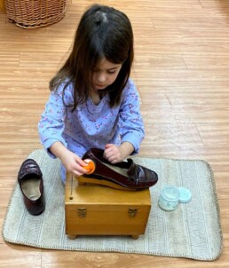 Lyonsgate Montessori School Casa student working hard at the Montessori Polishing Shoes activity.