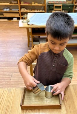 Lyonsgate Montessori School Casa student engaged in a pouring activity to build focus and motor control.