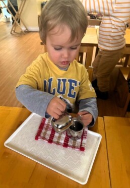 Lyonsgate Montessori School Toddler student engaged with a Montessori Pouring activity that develops motor skills and concentration.