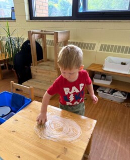 Lyonsgate Montessori School Toddler student working hard at a practical life activity to help care for the classroom.