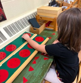 Lyonsgate Montessori School Casa student engaged in Small Metal Inset work with a material that is later used to learn about fractions in the Elementary program.