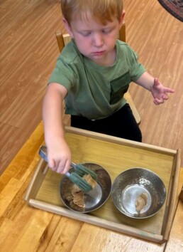 Lyonsgate Montessori School Toddler student using tongs to develop motor skills and build hand strength for success with later manipulatives and writing work.