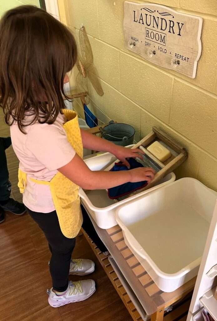 Lyonsgate Montessori School Casa student using laundry soap and a washboard to help care for the classroom cloths (and to learn about chemistry and completing tasks in a sequence).