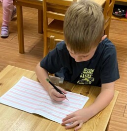 Lyonsgate Montessori School Casa student putting lots of work with Montessori materials to use as he moves to pencil and paper written work.