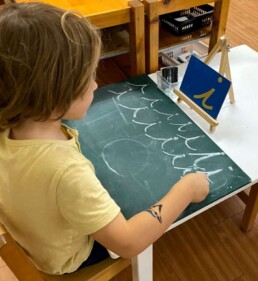 Lyonsgate Montessori School Casa student practicing writing the cursive letter 