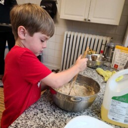 Lyonsgate Montessori School Elementary student mixing ingredients to bake muffins.