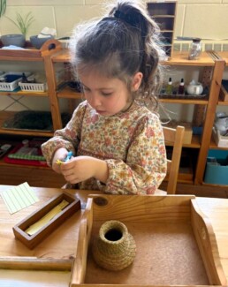 Lyonsgate Montessori School Casa student developing fine motor skills and concentration by cutting snippets with scissors.