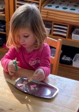 Lyonsgate Montessori School Casa student working at a cutting activity with scissors, developing both a practical skill and fine motor coordination.