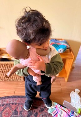 Lyonsgate Montessori School Toddler student giving some love to the classroom doll baby.