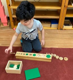 Lyonsgate Montessori School Casa student extending learning by using both the Montessori Cylinder Blocks and Knobless Cylinders together.
