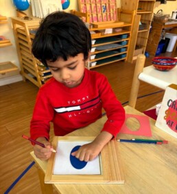 Lyonsgate Montessori School Casa student working with the Montessori Metal Insets material.