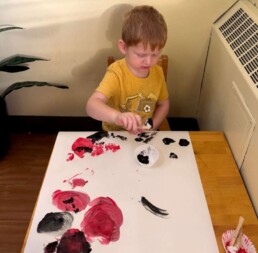 Lyonsgate Montessori School Toddler student painting poppies for the class's Remembrance Day art project.