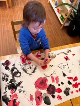 Lyonsgate Montessori School Toddler student painting poppies for the class's Remembrance Day art project.