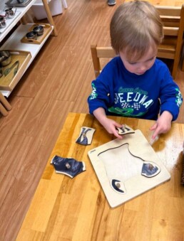 Lyonsgate Montessori School Toddler student working on a puzzle to help build visual and motor skills, and to prepare him for Montessori materials he will work with in the Casa program.