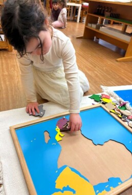 Lyonsgate Montessori School Casa student working with a Montessori Puzzle Map to build geography knowledge.