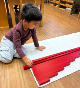 Lyonsgate Montessori School Casa student working with the Montessori Red Rods material.