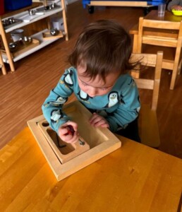 Lyonsgate Montessori School Toddler student learning to use a screwdriver and building motor control skills.
