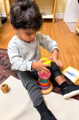 Lyonsgate Montessori School Toddler student building visual and motor control skills with a stacking activity.